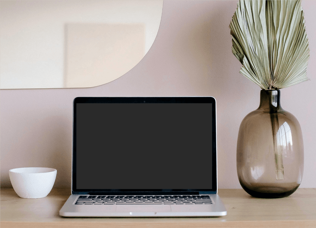 computer on a desk with vase on the right